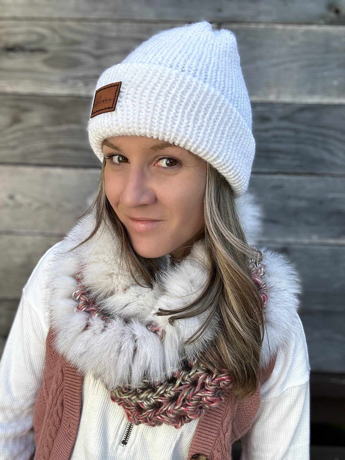 Femme avec foulard rose et fourrure recyclée blanche portant une tuque en tricot