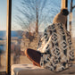 Femme regardant un couché de soleil sur Mont-Tremblant dans un chalet enveloppée dans une couverture